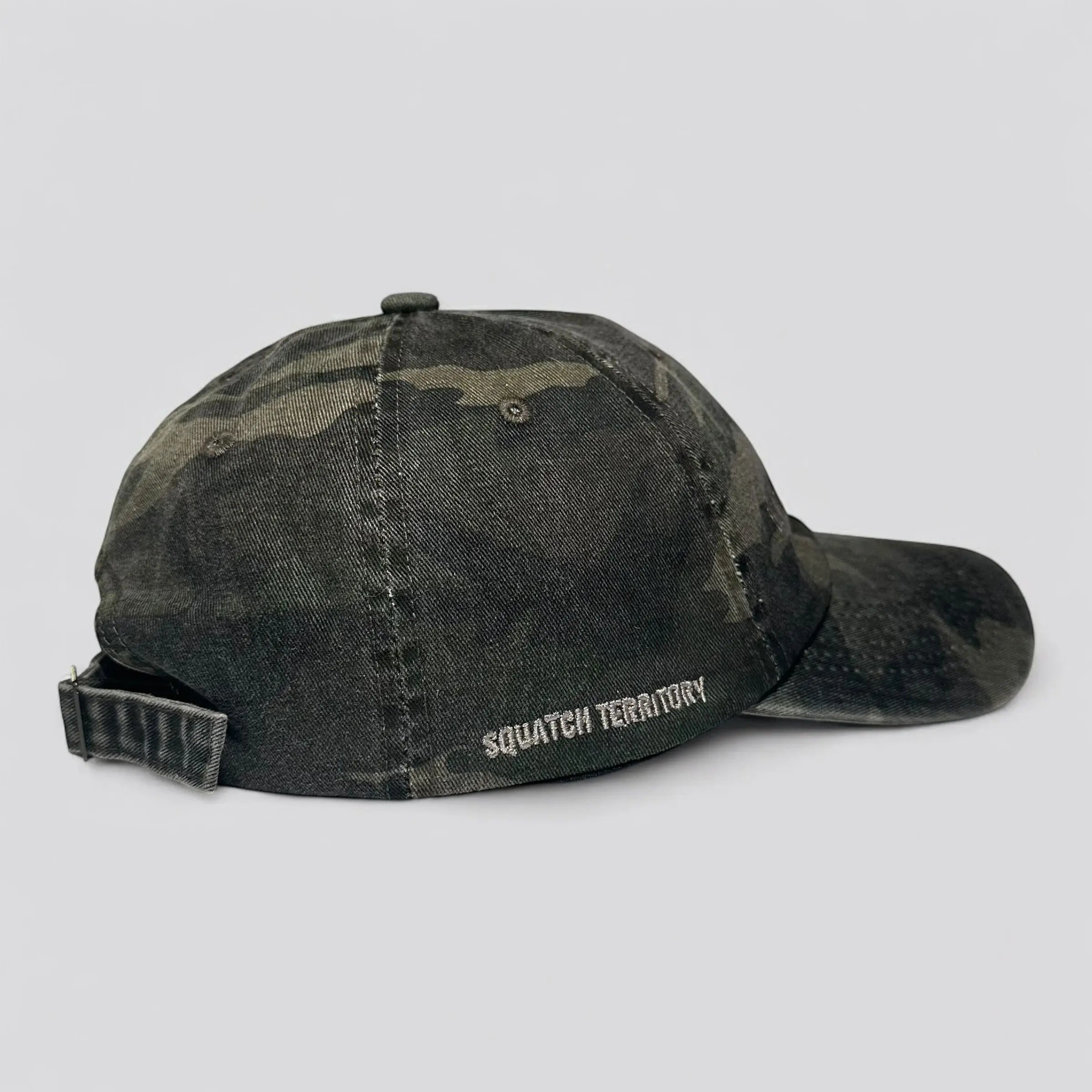 Side view of Backwoods Camo Dad Hat showing custom embroidery, "Squatch Territory", curved brim and durable camo material; ideal for off-grid explorers and trail lovers.