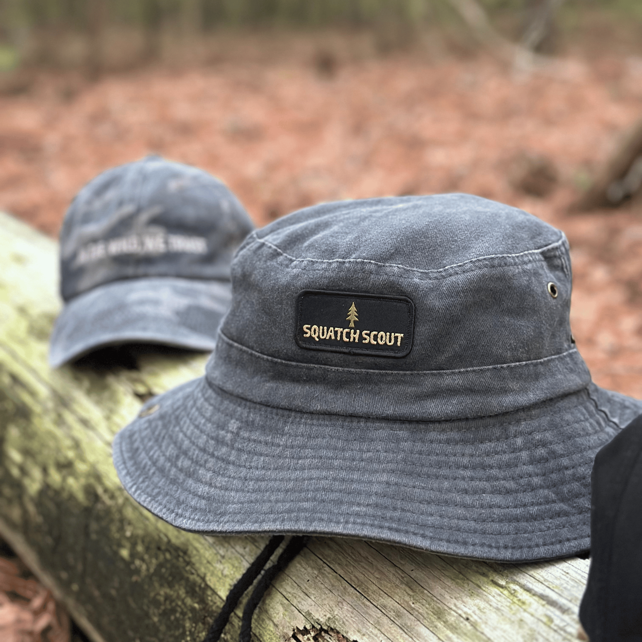 The Soul Squatch Squatch Scout Boonie Hat resting on a log in the woods — trail-ready bucket hat for adventurous explorers.