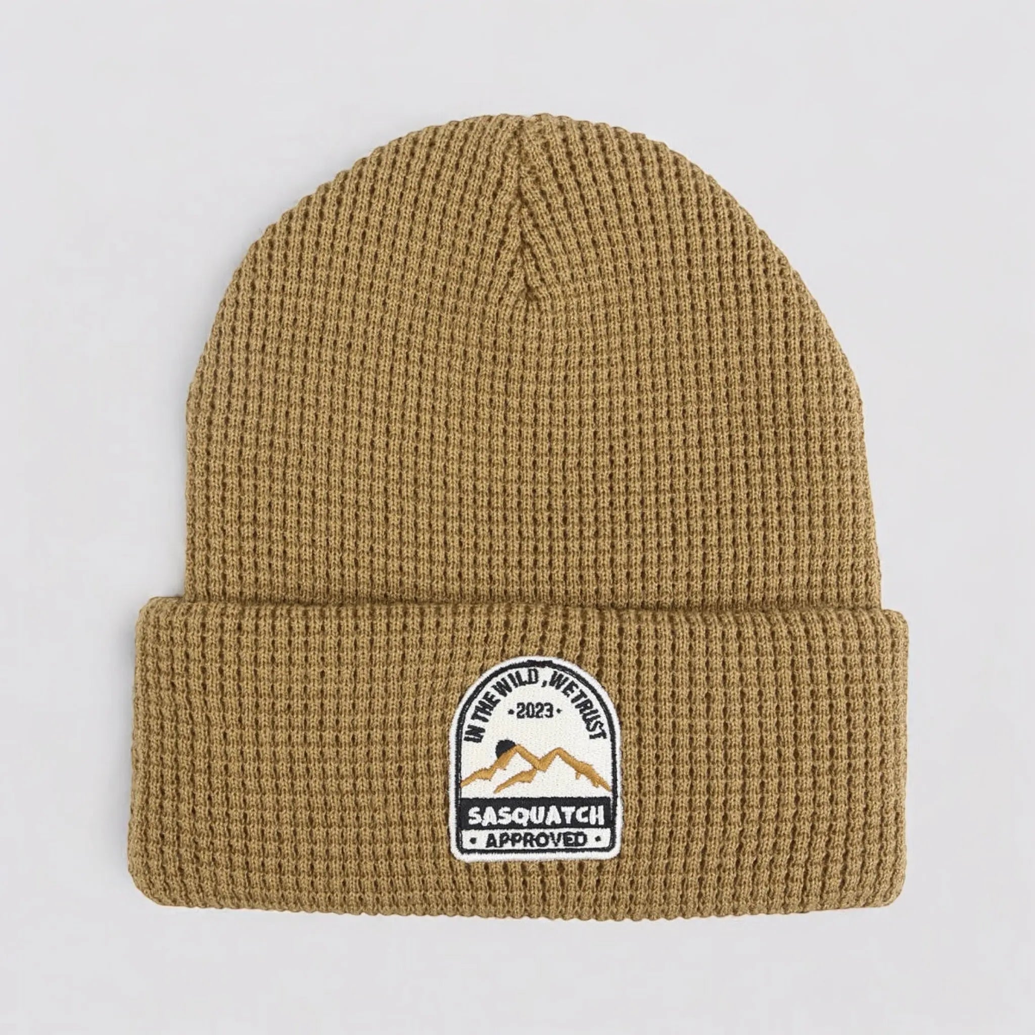 Flat lay of the Sunrise Summit Beanie in Muddy Path Taupe — taupe waffle-knit beanie with mountain sunrise patch.