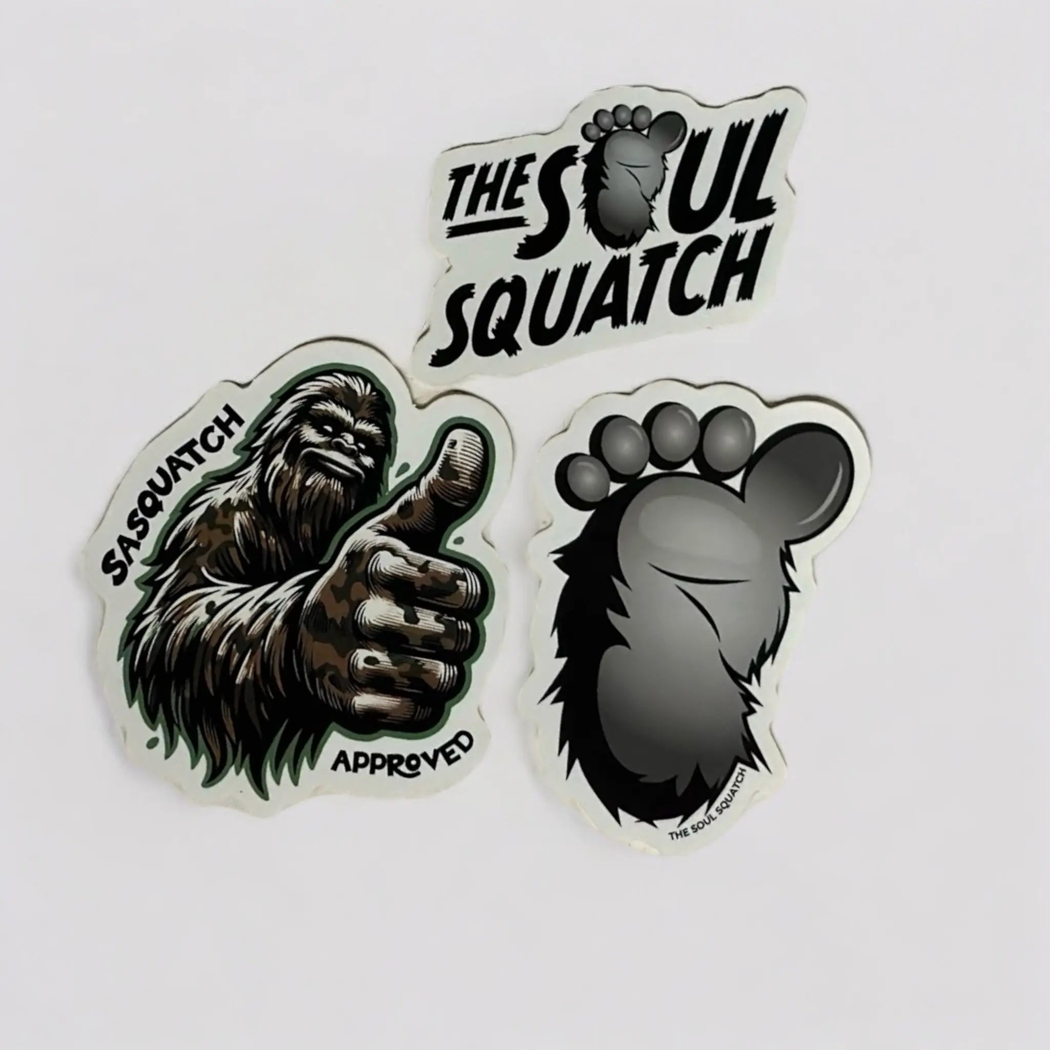 The Soul Squatch Sticker Pack featuring three rugged vinyl designs: logo, footprint, and Sasquatch thumbs-up — waterproof, scratch-resistant stickers for outdoor lovers, campers, and Bigfoot fans.