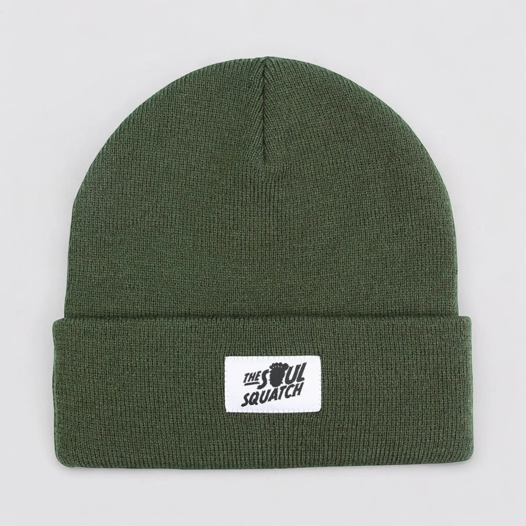 Flat lay of the Sasquatch Soul Beanie in Deep Forest Green — rugged green knit beanie with a cuffed edge and The Soul Squatch patch logo.