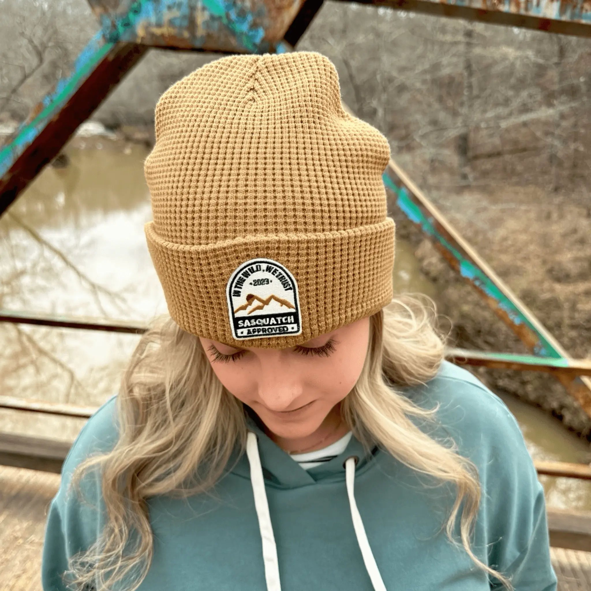 Woman wearing the Muddy Path Taupe Sunrise Summit Beanie — cozy taupe beanie with patch logo, perfect for Squatch-chasing and morning coffee in the woods.