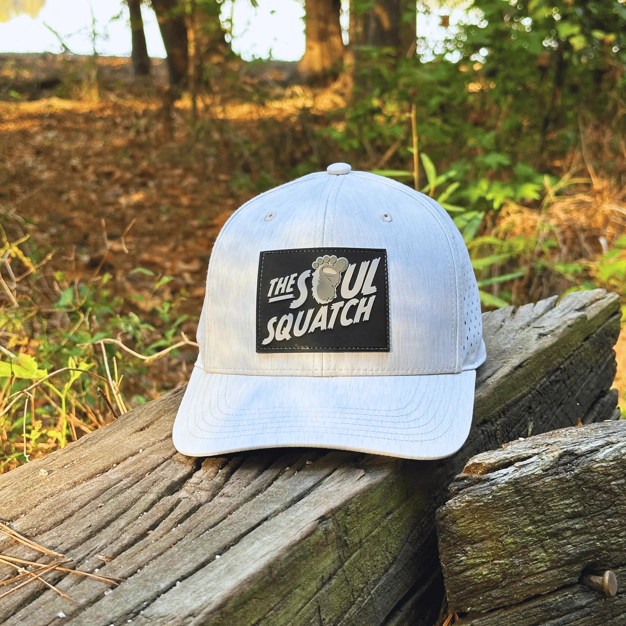 Sand-colored Pathfinder Mid-Profile Hat by The Soul Squatch placed on a forest trail log – lightweight and breathable for Bigfoot tracking in the heat.