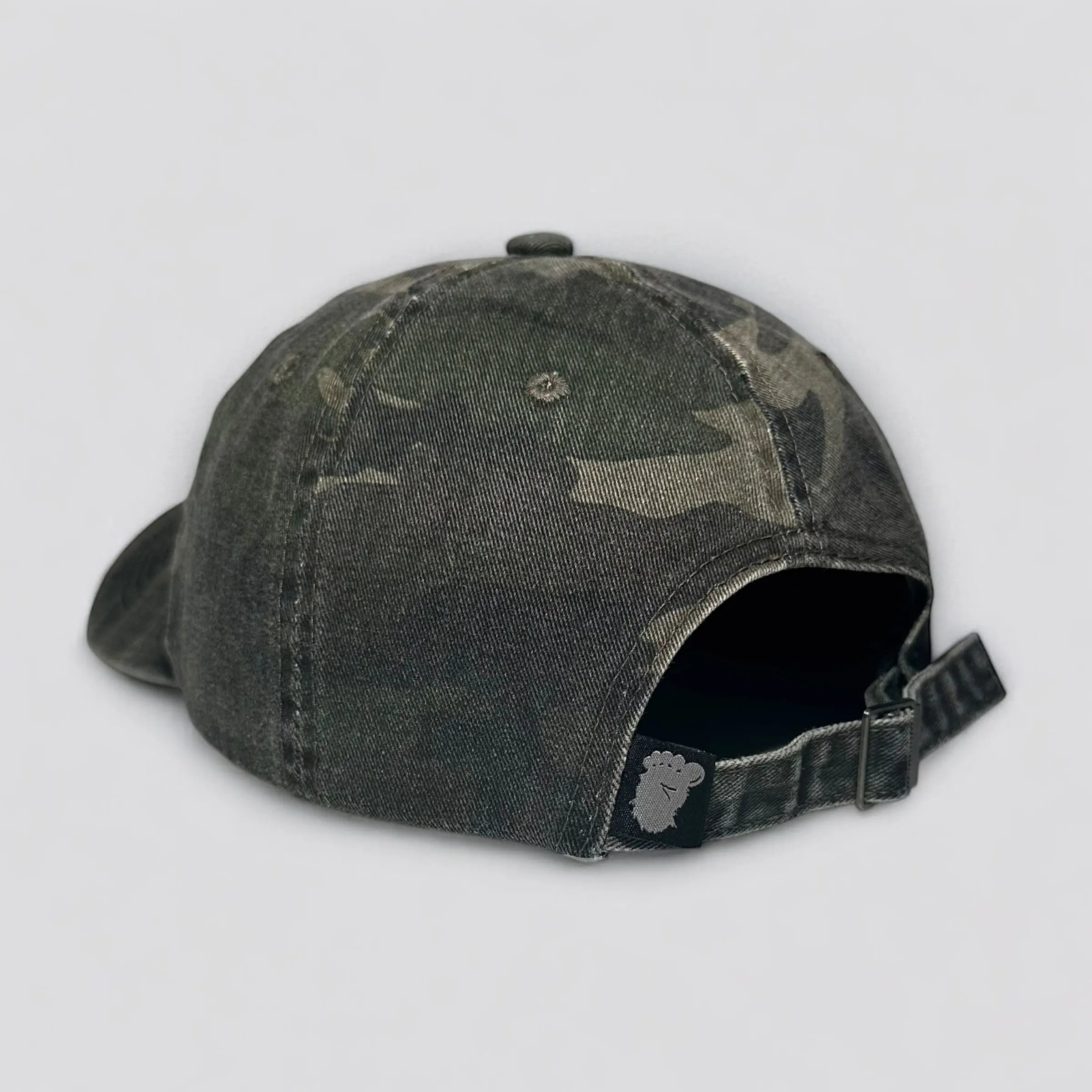 The Soul Squatch, back of camo dad hat featuring adjustable strap, metal buckle, and Squatch footprint back closure tag; designed for comfortable everyday adventure wear.