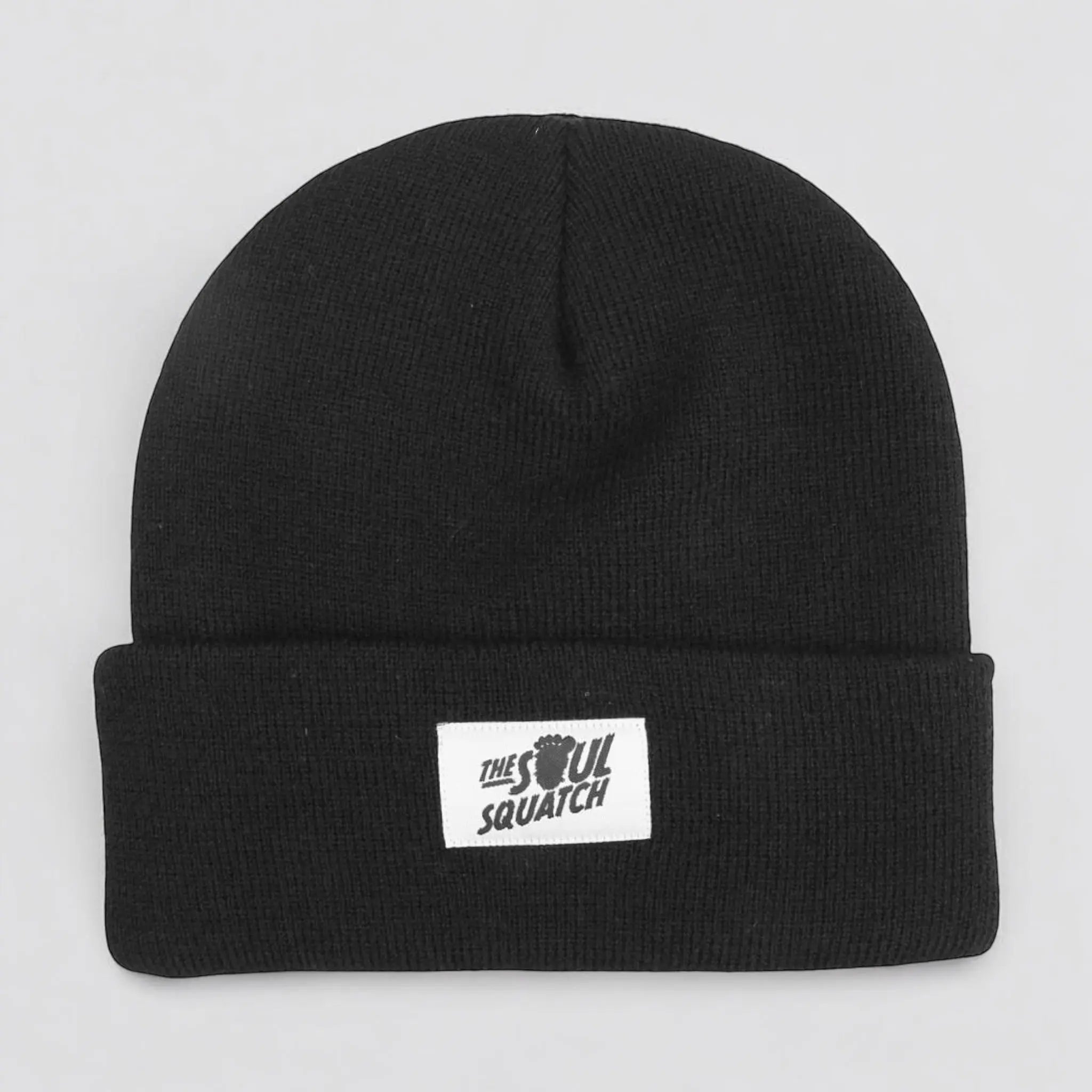 Flat lay of the Sasquatch Soul Beanie in Nightfall Black — soft black knit beanie with a cuffed edge and The Soul Squatch patch logo.