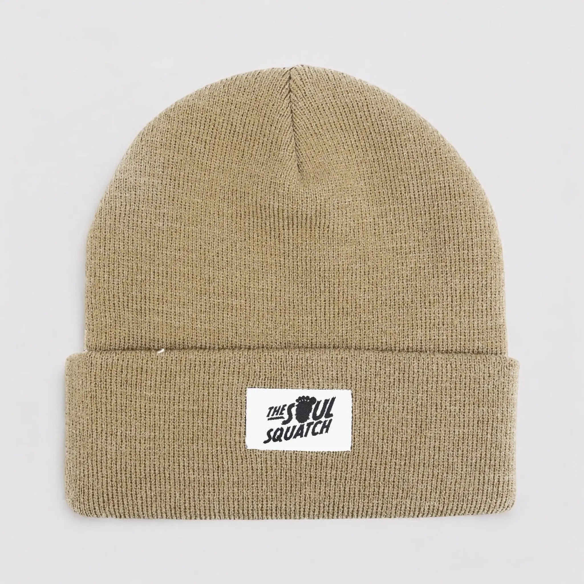 Flat lay of the Sasquatch Soul Beanie in Woodland Taupe — neutral tan knit beanie with a cuffed edge and The Soul Squatch patch logo.