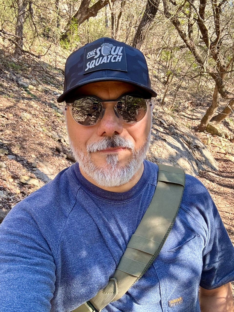 Man repping The Soul Squatch Pathfinder Mid-Profile Hat in Dark Camo on a wooded trail — rugged outdoor cap designed for believers.